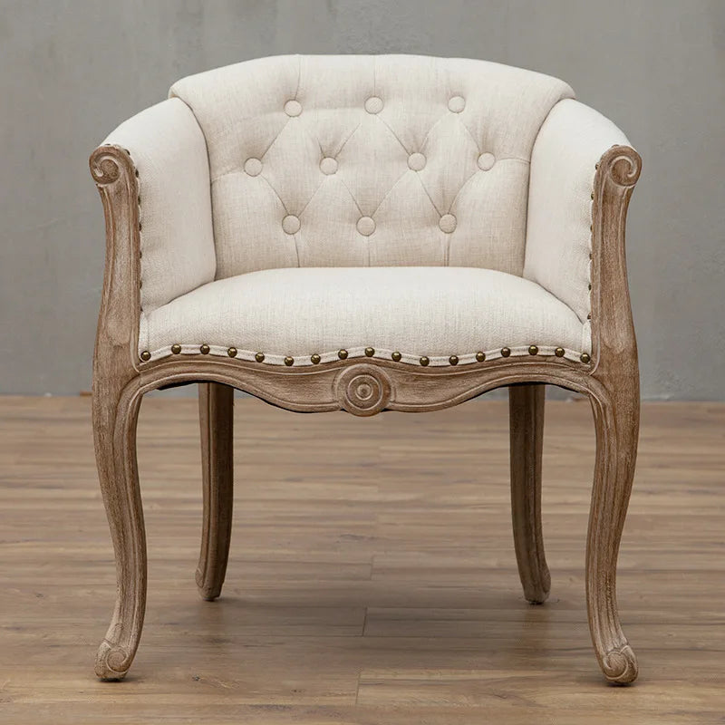 Luxury cream accent chair styled in an elegant family living room with warm neutral decor, marble fireplace, and visible Usfera branding