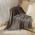 Cream knitted throw blanket folded neatly on a bed, ideal for bedroom layering, quiet routines, and cozy family comfort.