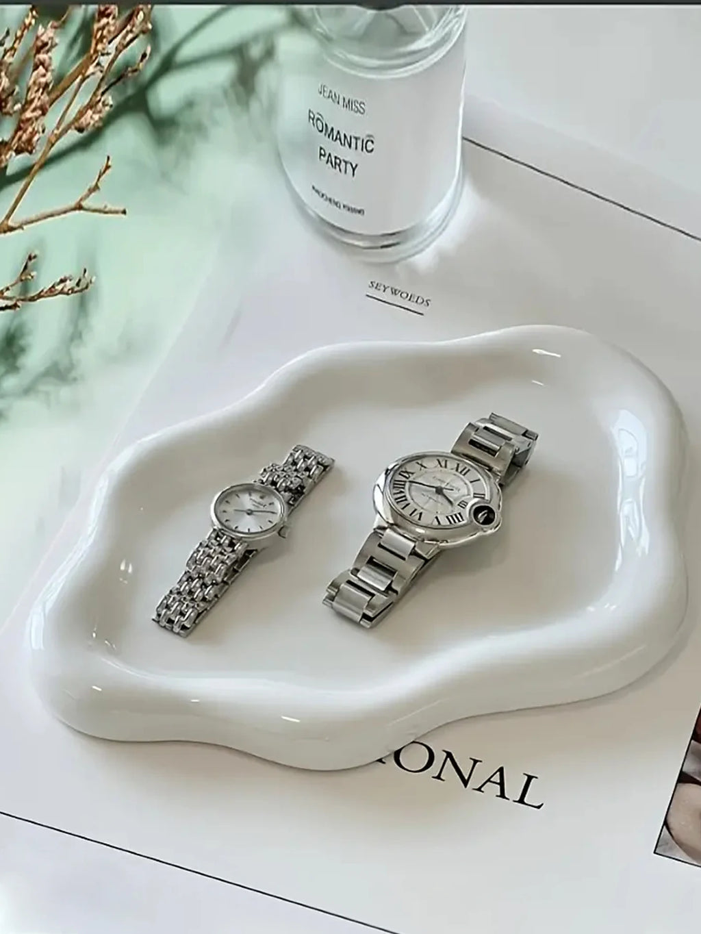 Glossy white ceramic jewelry tray styled on a calm luxury vanity with watches and soft neutral decor