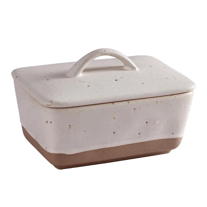 Ceramic butter dish with lid on a premium family breakfast table with bread, butter, coffee, and warm neutral decor