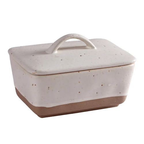 Ceramic butter dish with lid on a premium family breakfast table with bread, butter, coffee, and warm neutral decor