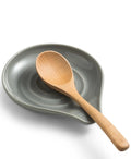 Ceramic spoon rest with wooden spoon on a warm neutral kitchen counter with premium calm-home styling
