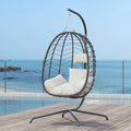 Luxury outdoor egg chair with metal stand and soft cushions styled on a premium seaside terrace