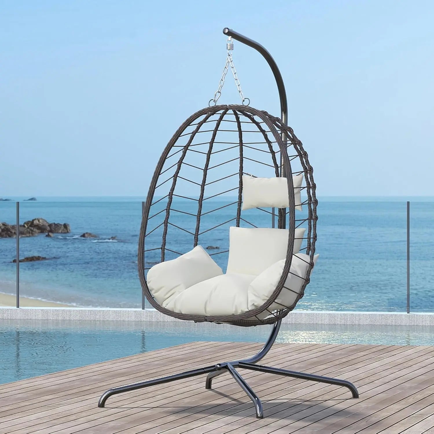 Luxury outdoor egg chair with metal stand and soft cushions styled on a premium seaside terrace