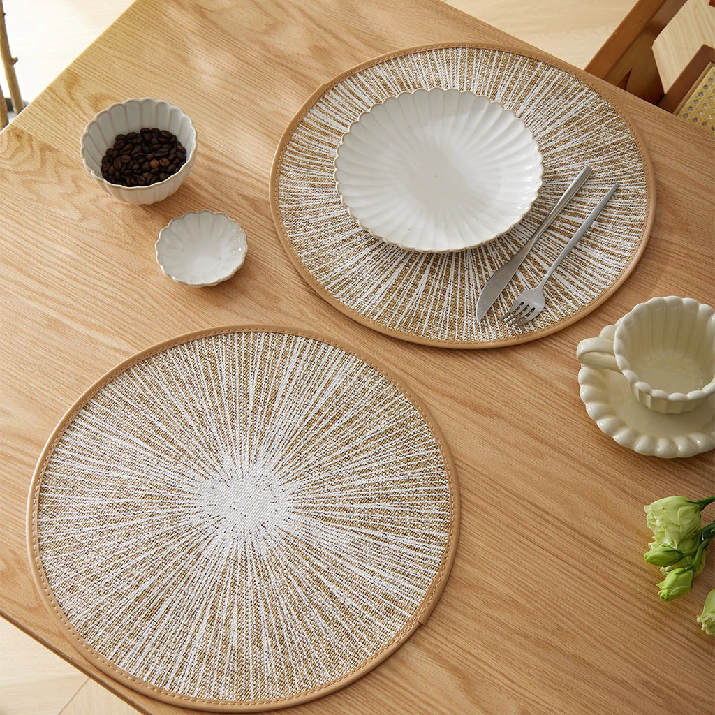 Round burlap macrame placemats styled on a light wood dining table with bowls, cups, and neutral tableware