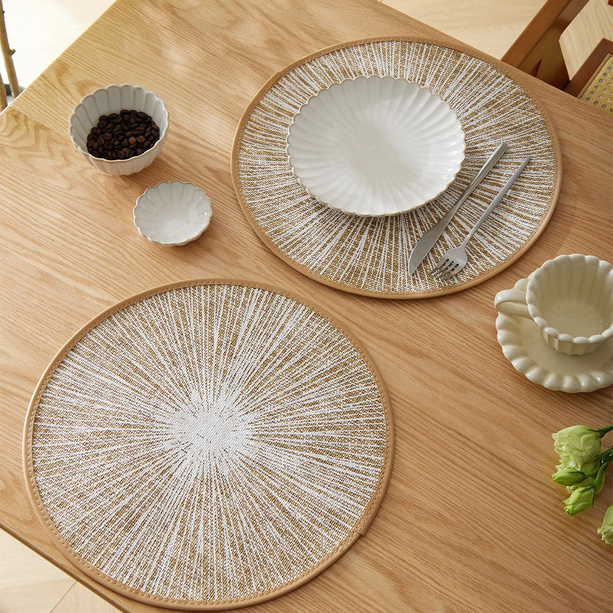 Round burlap macrame placemats styled on a light wood dining table with bowls, cups, and neutral tableware