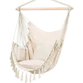 White macrame hanging chair styled in a calm luxury outdoor terrace with neutral cushions, wood accents, and soft natural light