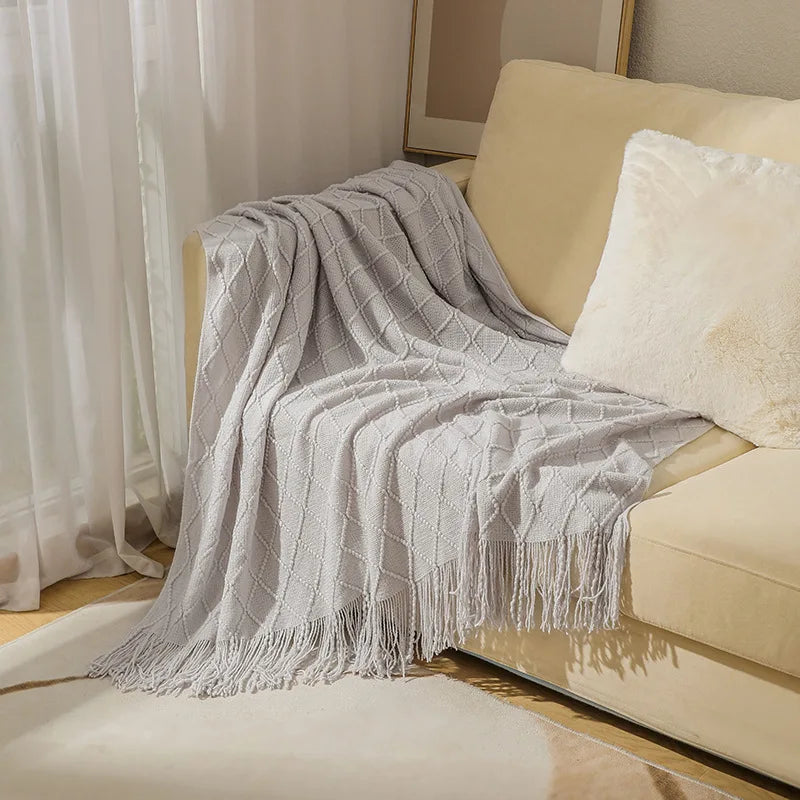 Close-up of a Nordic knit throw blanket showing soft woven texture and elegant tassel detail for premium home styling.