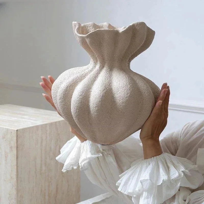Sculptural ivory ceramic vase with textured pleated design on a dark minimalist background