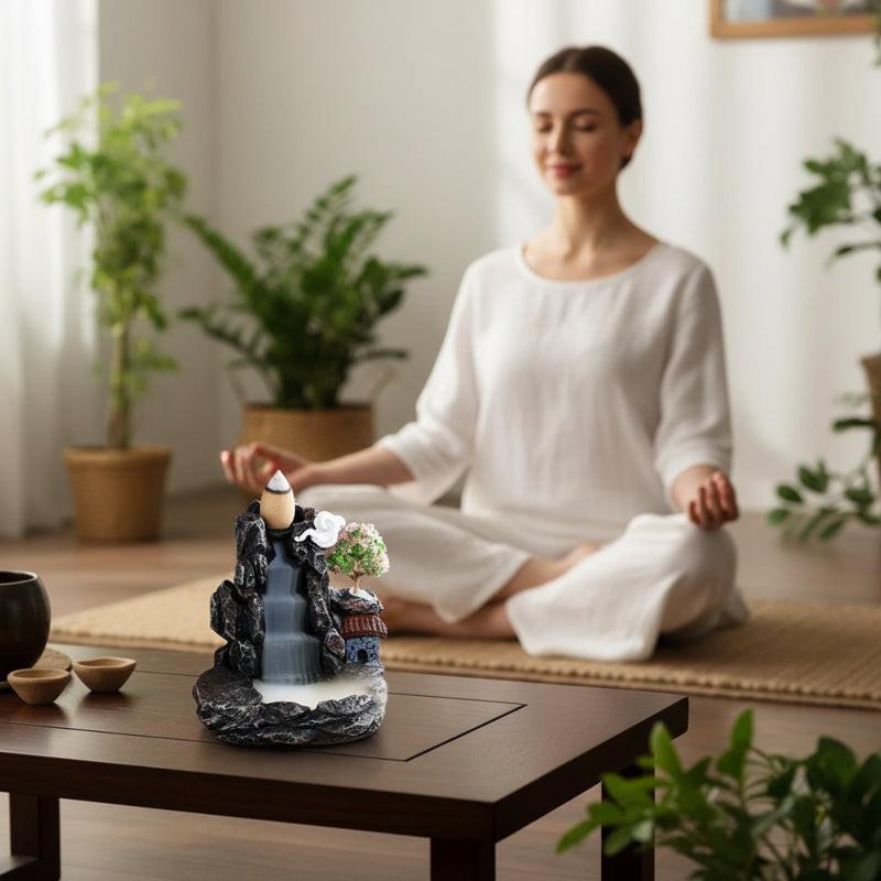 Woman meditating beside zen backflow incense burner with waterfall smoke effect — Usfera calm home
